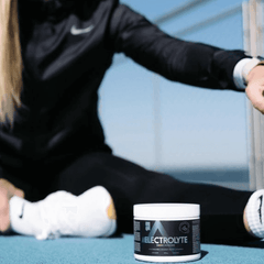 a woman sitting on the ground next to a jar of electrolyte